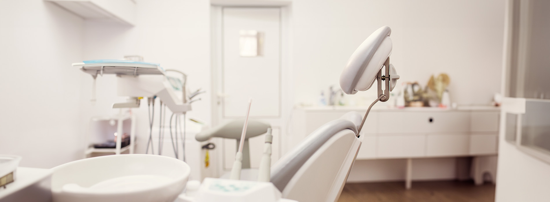 The image shows a modern dental clinic interior with various pieces of equipment, including a dental chair and an X-ray machine.